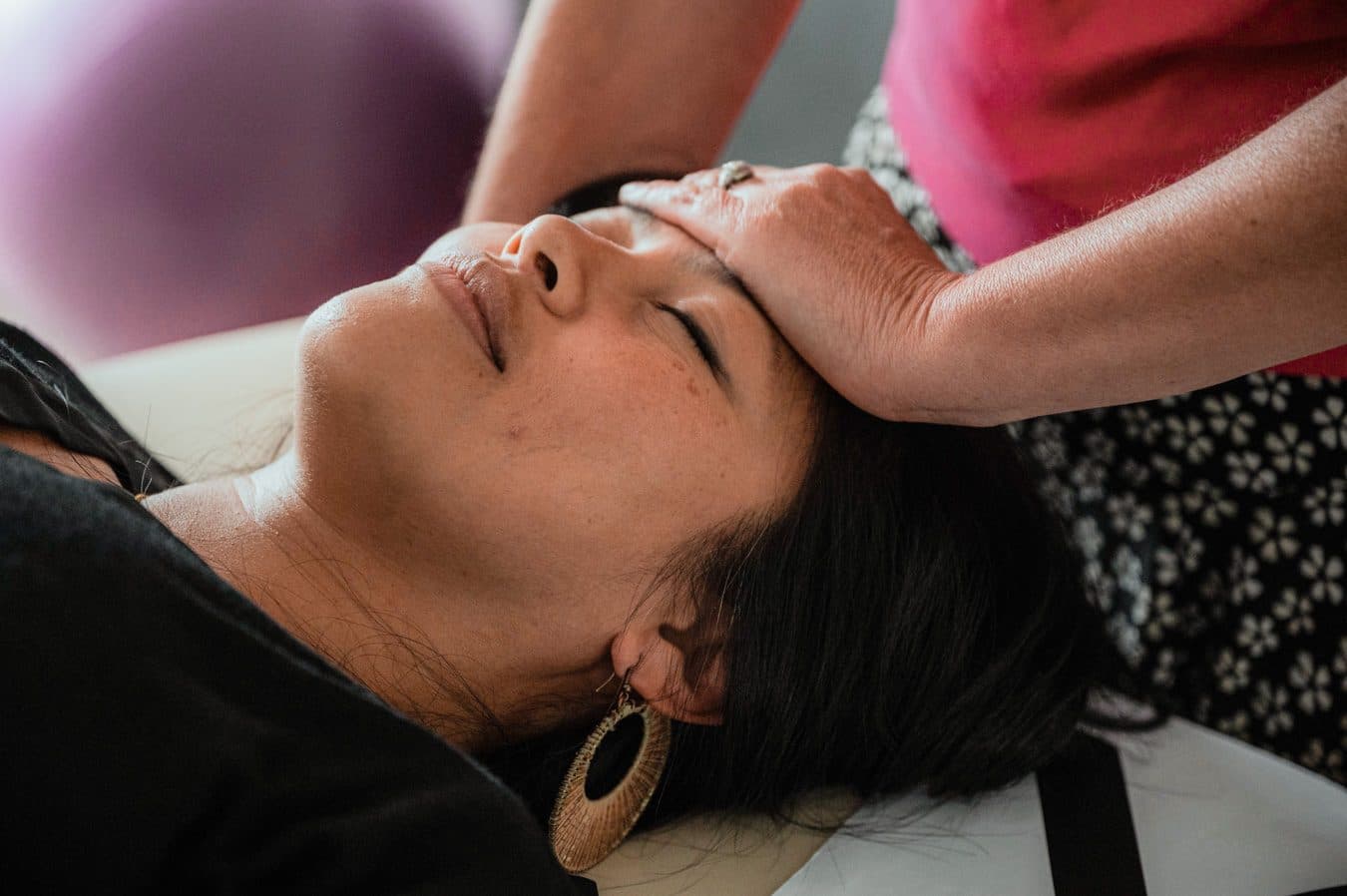 Hands resting on a woman's head as she relaxes with her eyes closed