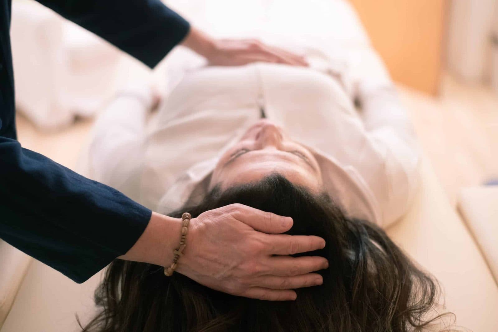 Practitioner's hand resting on a relaxed woman's head