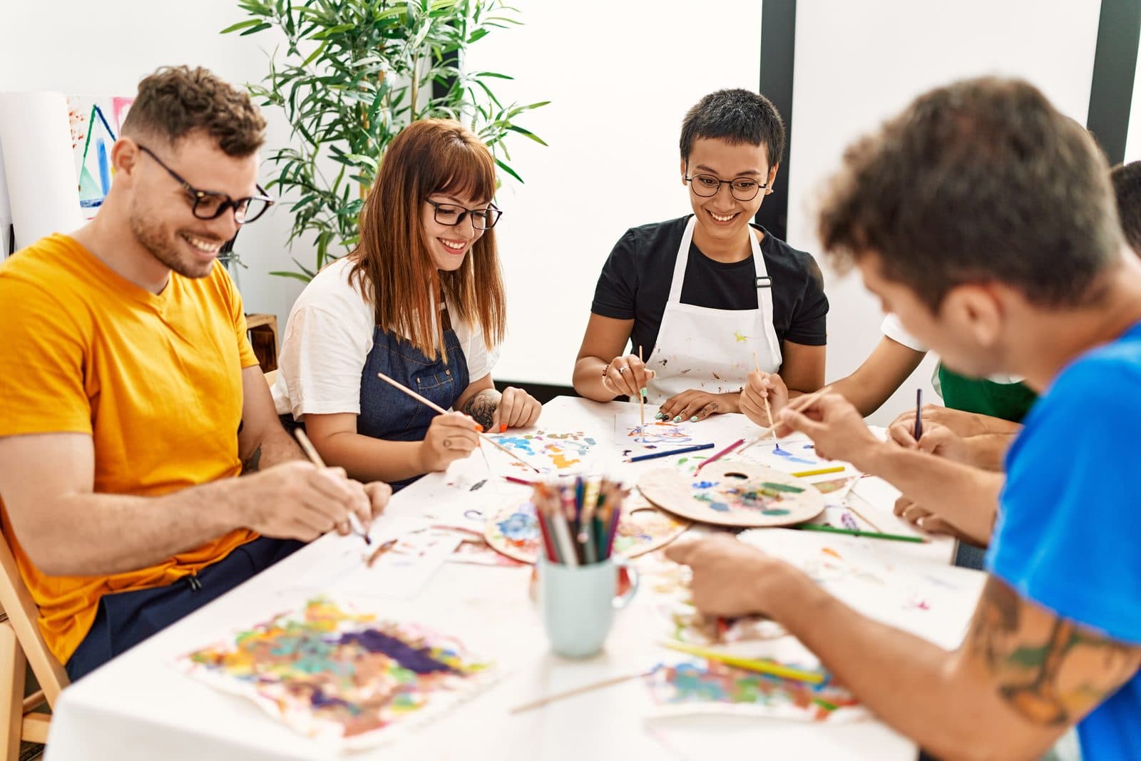 Group painting together around a table in an art therapy workshop
