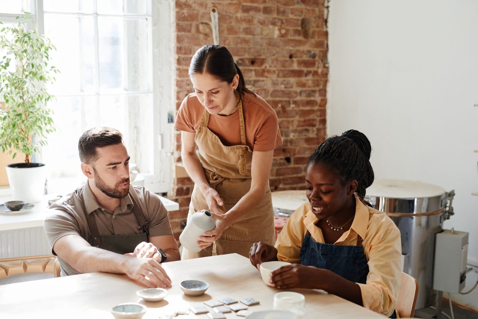 Participants working with clay and brushes in a bright studio