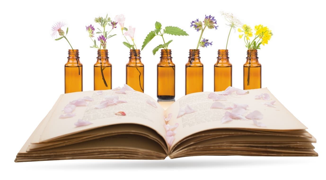 Row of flower essence bottles on an open book of flower illustrations