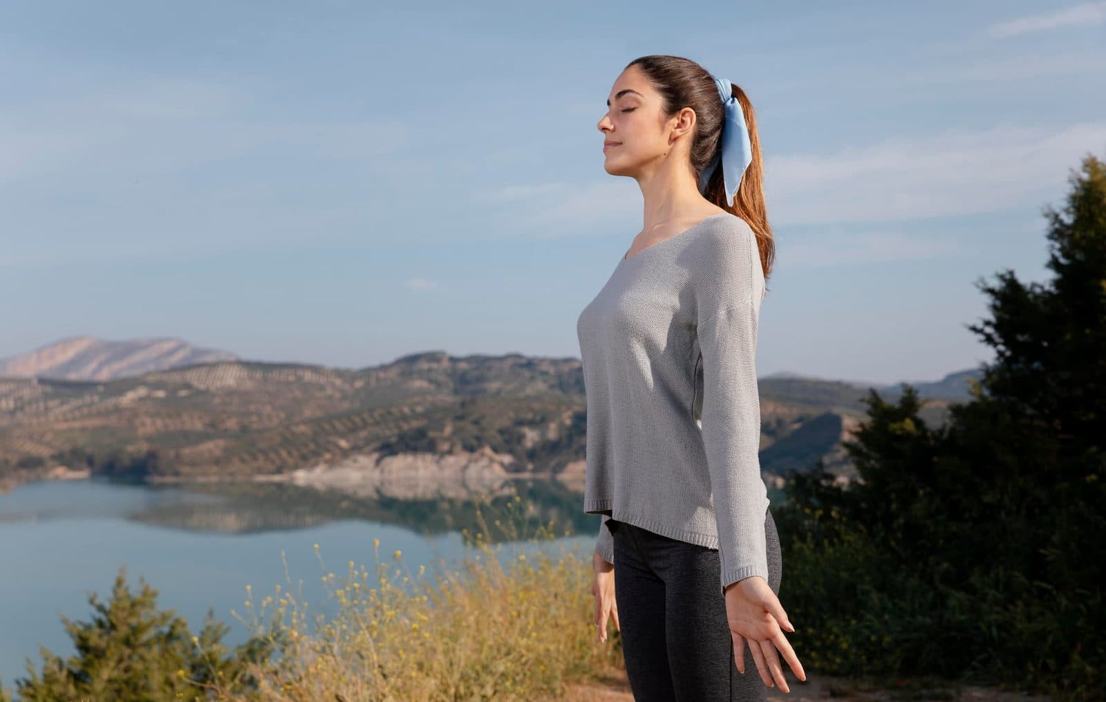 Woman breathing deeply outdoors above a lake