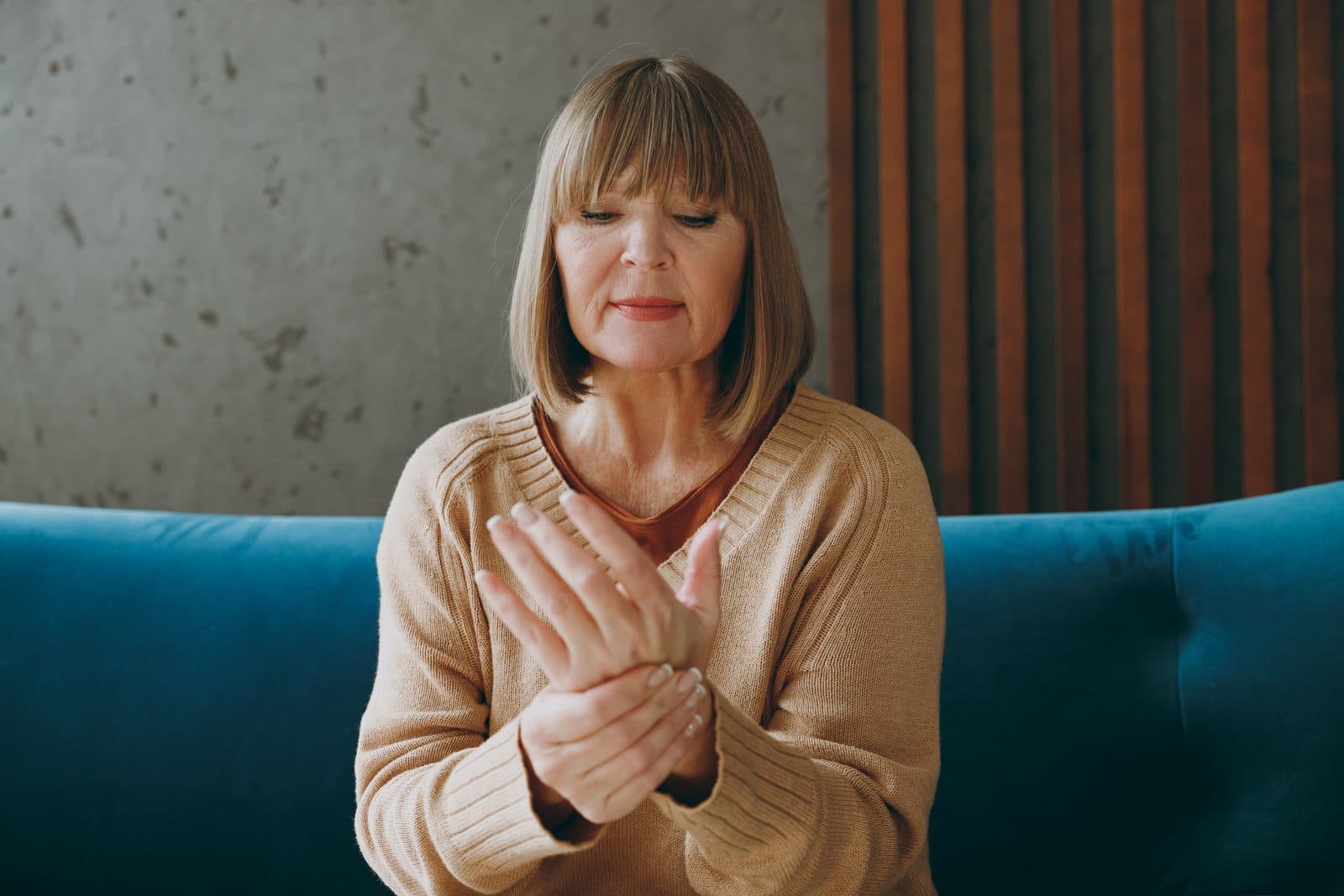 Woman sitting on a sofa pressing points on her hand