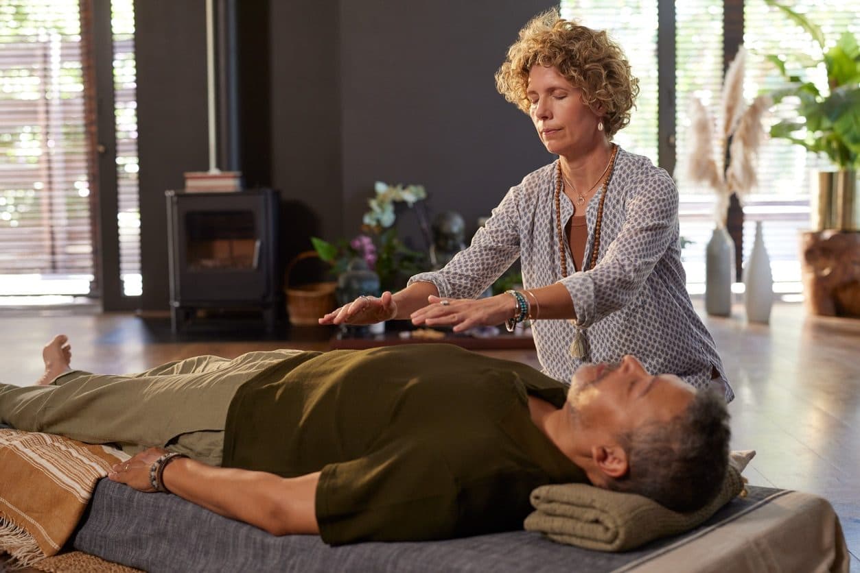 Practitioner holding her hands above a client lying on a mat