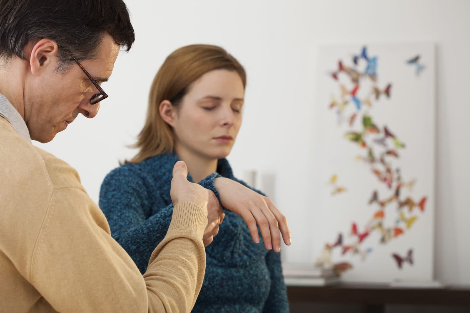 Hypnotherapist guiding a client into relaxation with a light touch on the shoulder