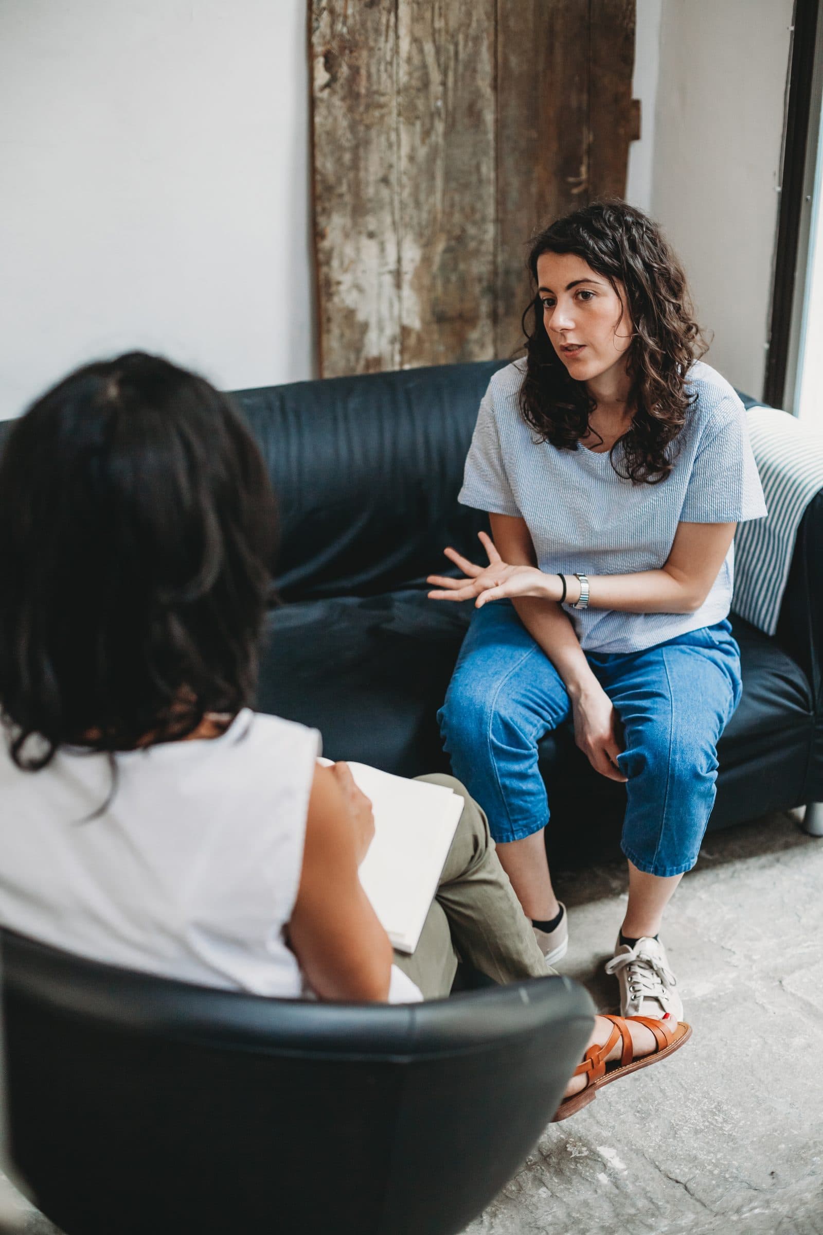 Client talking with a practitioner on a sofa during a session