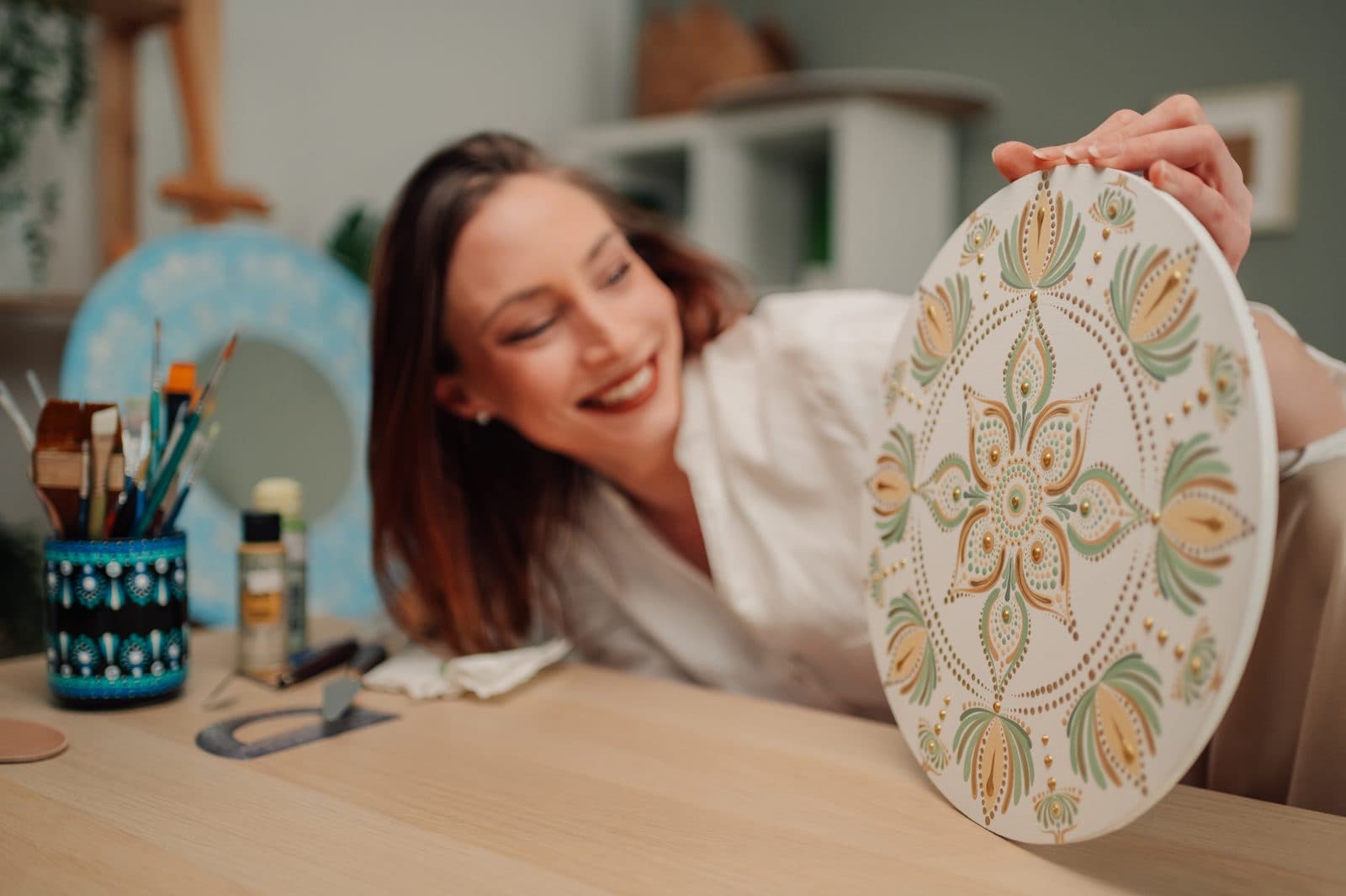 Artist smiling at her finished dot mandala painting