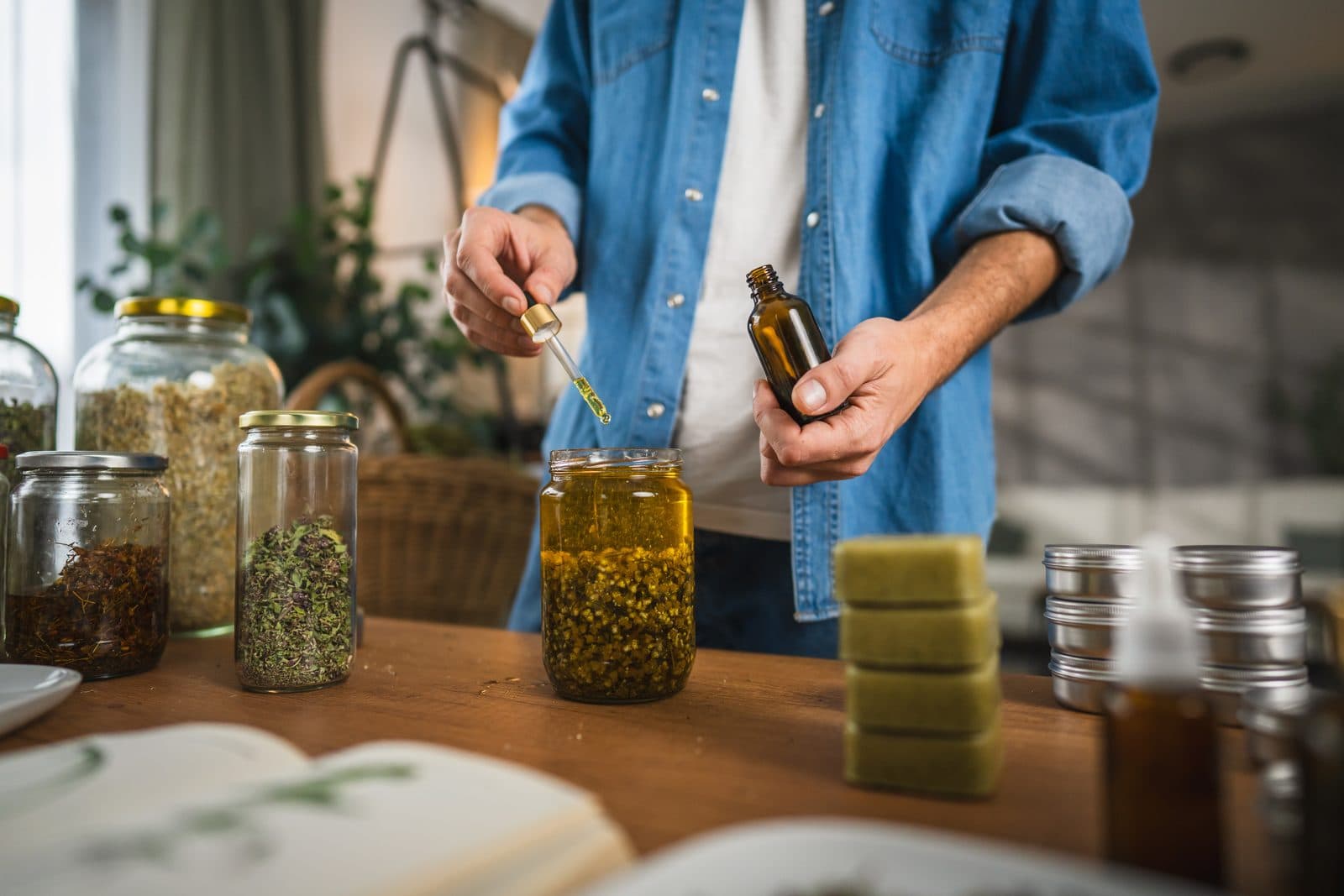 Herbalist preparing homemade plant preparations in glass jars