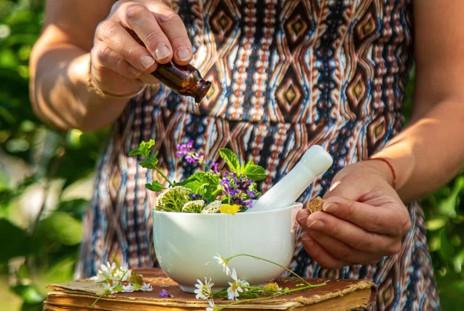 Woman grinding fresh herbs in a mortar outdoors