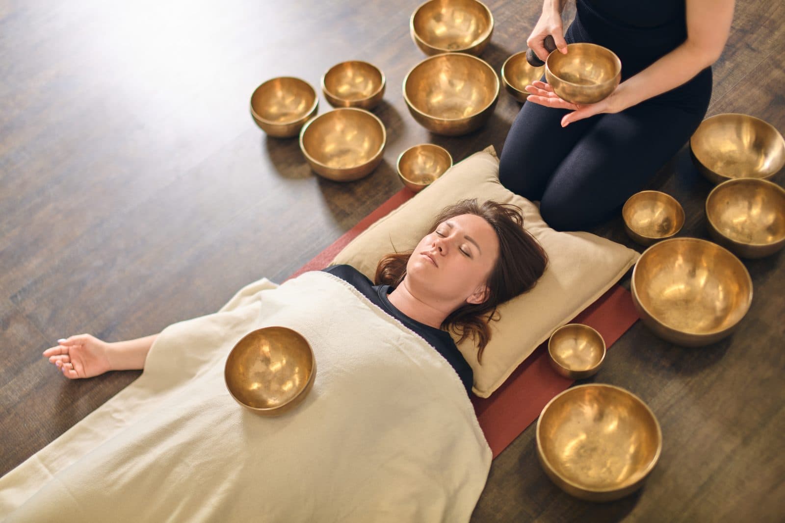 Woman lying relaxed among singing bowls during a sound bath