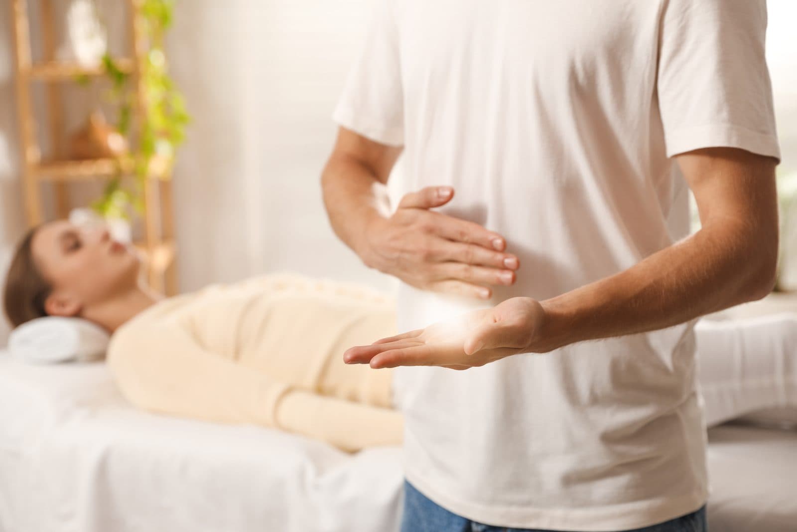 Reiki practitioner's hands held above a client resting on the treatment table