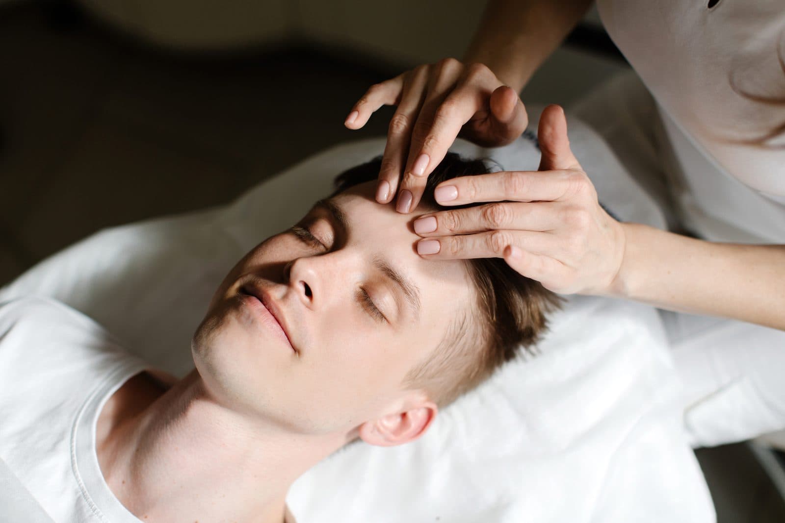 Practitioner's fingertips resting on a client's forehead